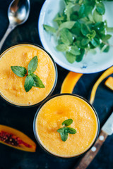 From above view of two glass orange smoothie with leaves of fresh mint