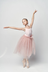1456844 girl ballerina in a pink tutu dancing against a white background