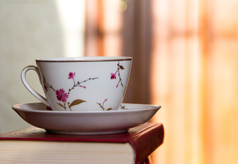 Porcelain cup with coffee and book. Close-up.