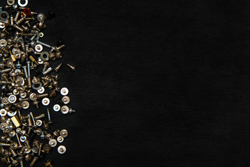 Silvery bolts and screws on a black board