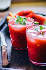 From above view of two glass of red smoothie with ice and fresh leafs mint