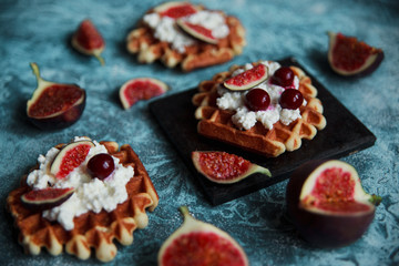 Still life of belgian biscuit waffles with cottage cheese, fresh figs and cherry. Healthy vegetarian breakfast.