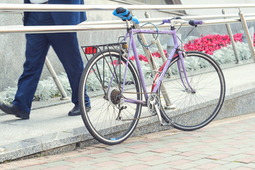 Obraz premium Old road bike of pink color with a ridiculous seat rewound blue electrical tape. Cycling or commuting in city urban environment, ecological transportation concept