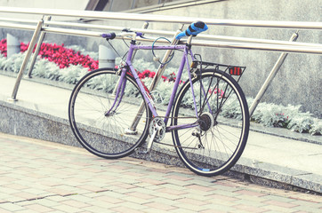 Fototapeta na wymiar Old road bike of pink color with a ridiculous seat rewound blue electrical tape. Cycling or commuting in city urban environment, ecological transportation concept