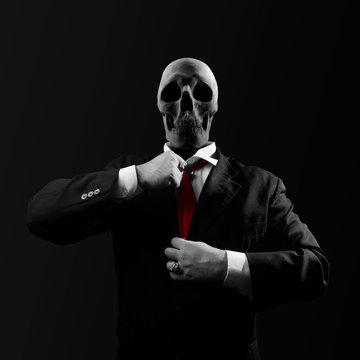 Black and white politician man with skull head in black suit straightens a red tie on black background.