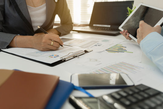 Businessman with finger touching screen of a digital tablet at office on table with document graph data, Businesswoman calculate about cost, Finance managers task, Concept finance investment