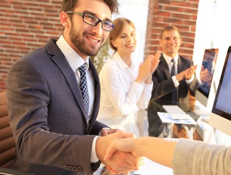 businessman shaking hands with a business partner sitting near your desktop