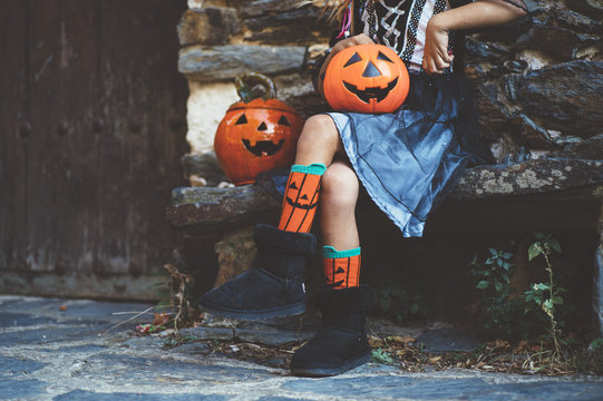 Crop little girl in witch costume sitting on bench