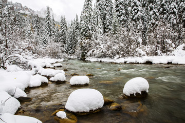 snow covered rocks in a cold mountain river  - 171376405
