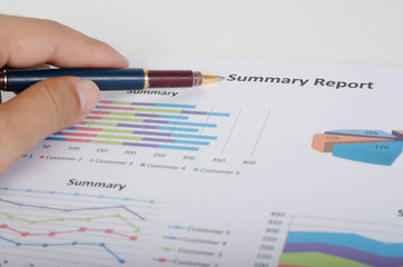 Close-up of businessman hand with graphs and charts analyzing concept.