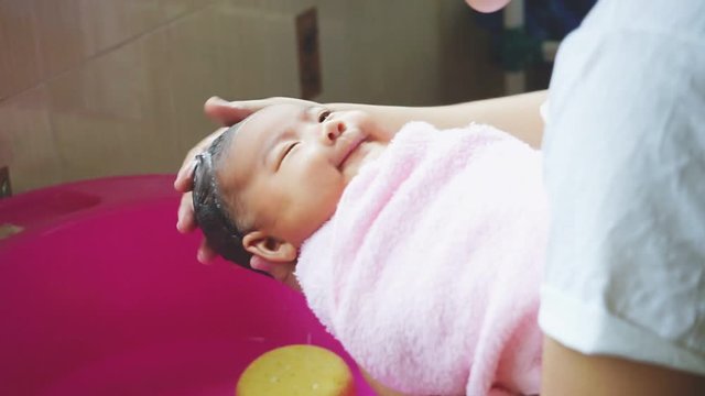 Mother hands washing baby head with shampoo