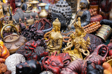 Nepalese religious statuettes made of brass surrounded by other handicrafts and souvenirs on the...