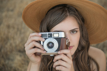 Beautiful, young woman taking photo with vintage camera, close up