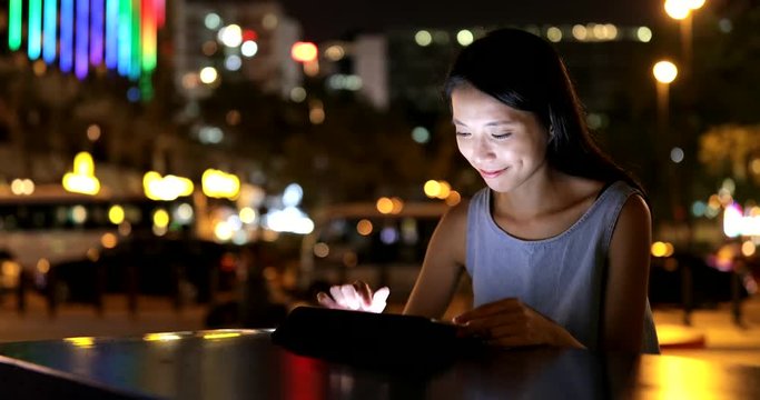 Woman focus on using digital tablet in city at night
