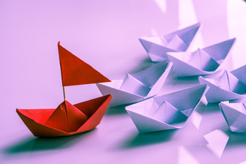 Leadership concept with red paper ship leading among white