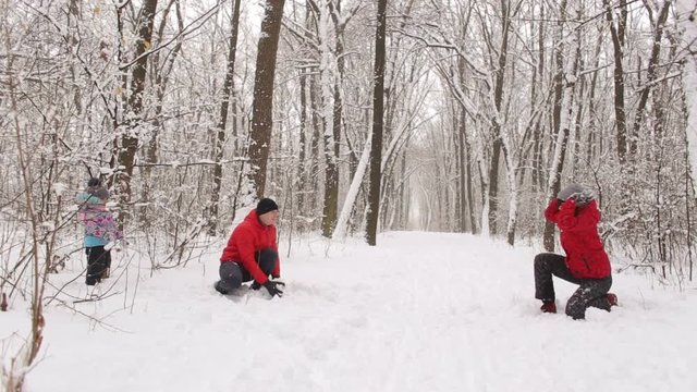 Big happy family play snowballs in winter Park. Happy family playing snowballs in the snowy woods.