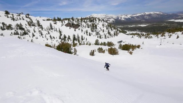 Snowboarder rides up a large ramp and does a backside triple cork