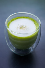 Cup of hot matcha green tea with milk foam.
