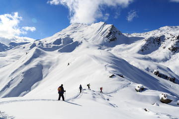 Group of people hiking on snowshoes and mountain snow panorama with blue sky in Stubai Alps, Austria