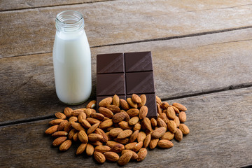 milk in bottle, chocolate and almond on wooden