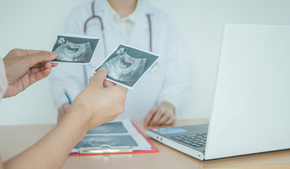 Fototapeta premium Doctor explaining ultrasound scan to pregnant woman in hospital.