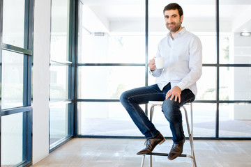 Young business man sitting on a stool in office