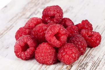 Red fruits of raspberry on wooden plank background, close up