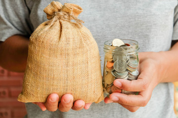 save money for investment concept Hand holding money in jar