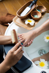 Manicure and pedicure series: Pedicurist brushing customer's foot in pedicure bowls
