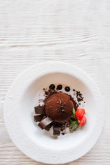 Chocolate fondant with decoration from strawberry and mint on wooden background. Delicious dessert serving in restaurant, top view with free space above