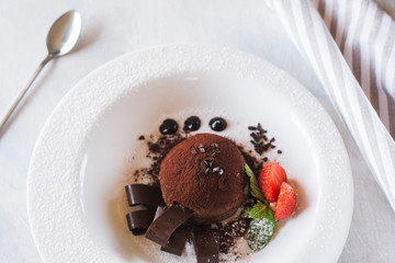 Delicious chocolate dessert on white plate with decoration from strawberry and mint. Fondant...