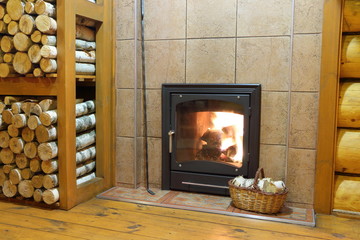 A wood burning stove. Wood stove and firewood in rural wooden house.