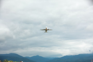 Fototapeta na wymiar a passenger plane flies into the sky amid the mountains