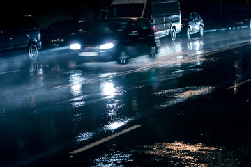 blurred car driving on street during heavy rain. night traffic in city. 