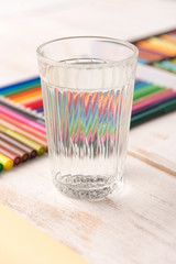 Close up of glass with water standing near colorful markers