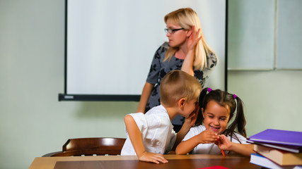 Small schoolkids do a homework. They pupils of an elementary school. On a desk there are school...