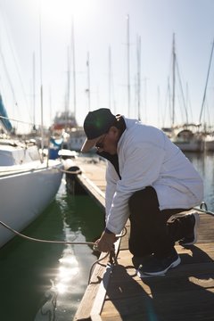 Yachtsman tying rope on the pier
