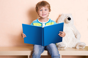 Cute little boy is reading book at home © ulza