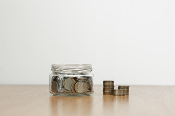 Glass jar full of coins and stack of penny