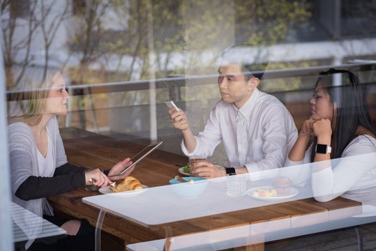 Businesswoman with colleagues having food seen through glass