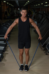 Fototapeta na wymiar Fitness man exercising with stretching band in the gym. Muscular sports man exercising with elastic rubber band.