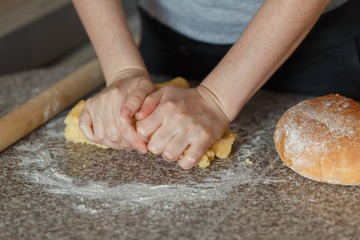 Girl's hands kneading dough in flour on table