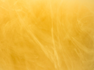 Yellow smoke, ink in water. Abstract colored background. Frozen movement color flow of paint. Horizontal photo with soft focus, blurred backdrop.