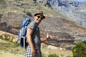 Fototapeta na wymiar Smiling hiker in hat looking at camera, gesturing
