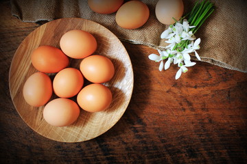 Easter background. Rustic wooden table with plate, egg, flowers and cutting board . Top view