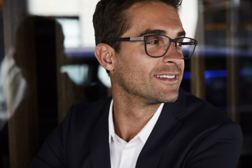 Smartly dressed man in jacket and glasses, looking away