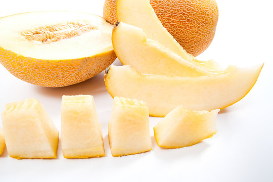 Close up view of whole, half and sliced honeydew melon tropical fruit isolated on a white background.