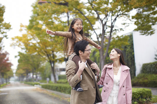 Family of three in park, daughter on father's shoulders