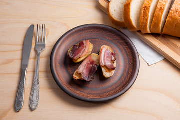 Baked potatoes with slices of bacon on wooden background. Slices of white bread on cutting board.