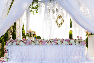 Served wedding banquet table in the garden decorated white lace, pink flowers and silk. newlyweds table